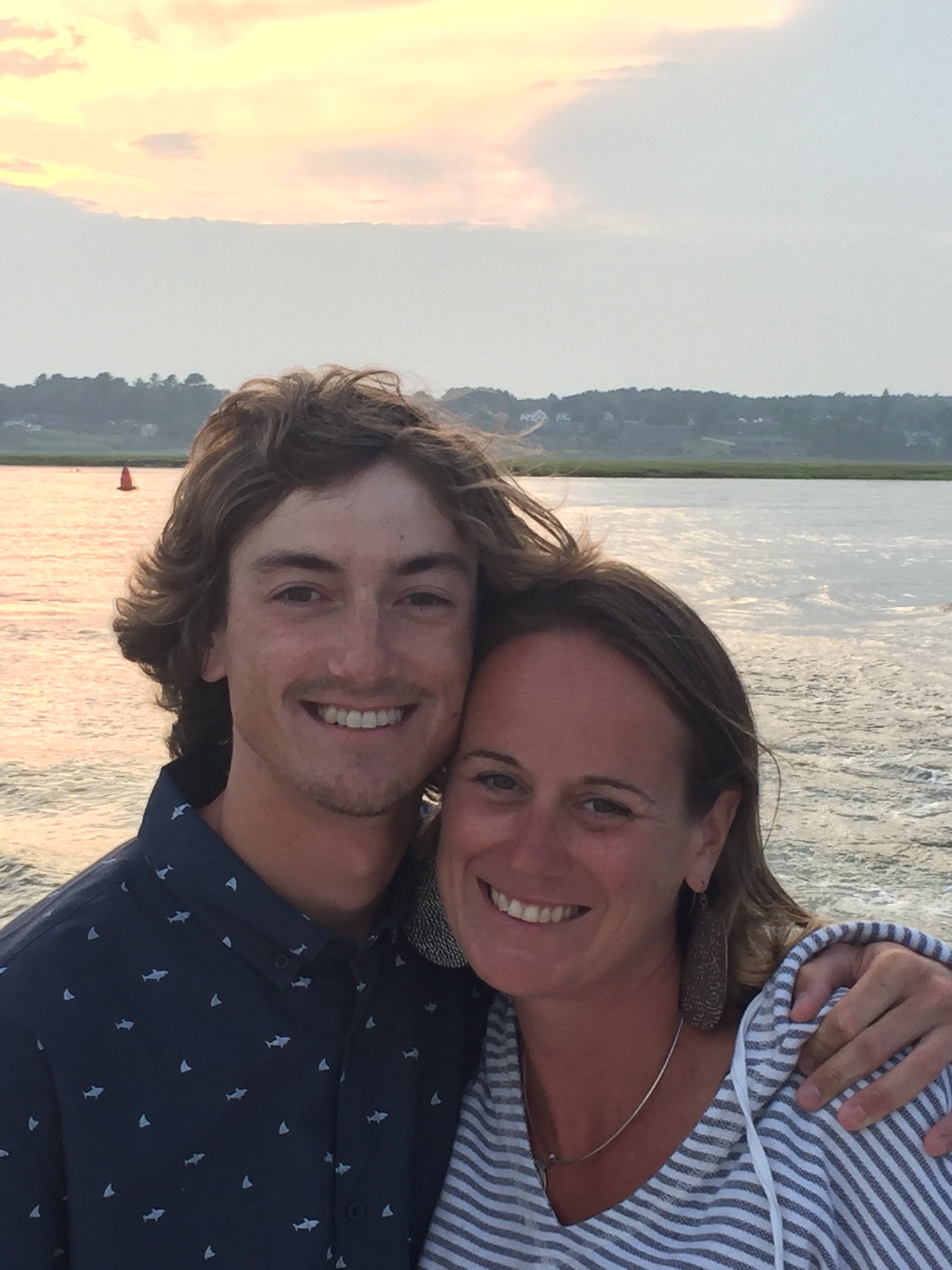 Ashley and Cody smiling by the water at sunset